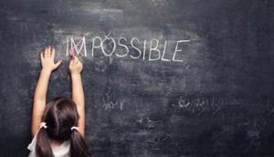 A girl writes the word possible on a blackboard