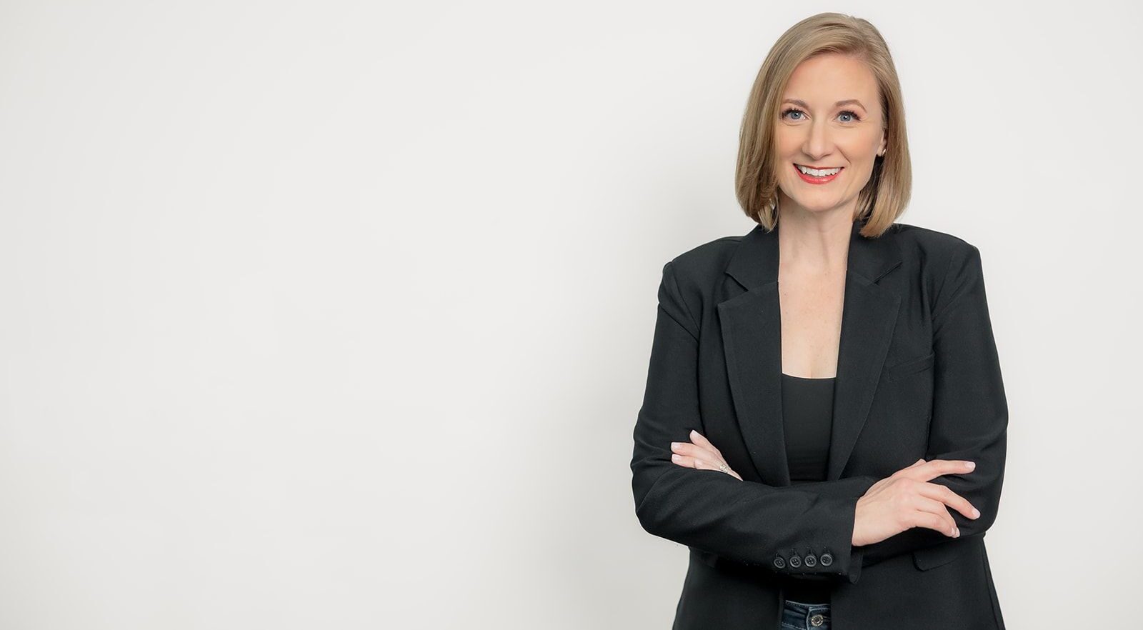 Julie Cropp Gareleck, an author, entrepreneur, and CEO smiles in front of a white wall